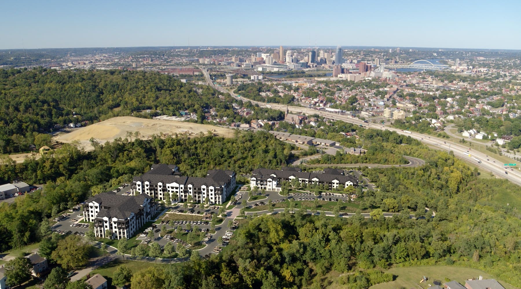 aerial of property showing nearby lush forest and nearness to downtown city skyline