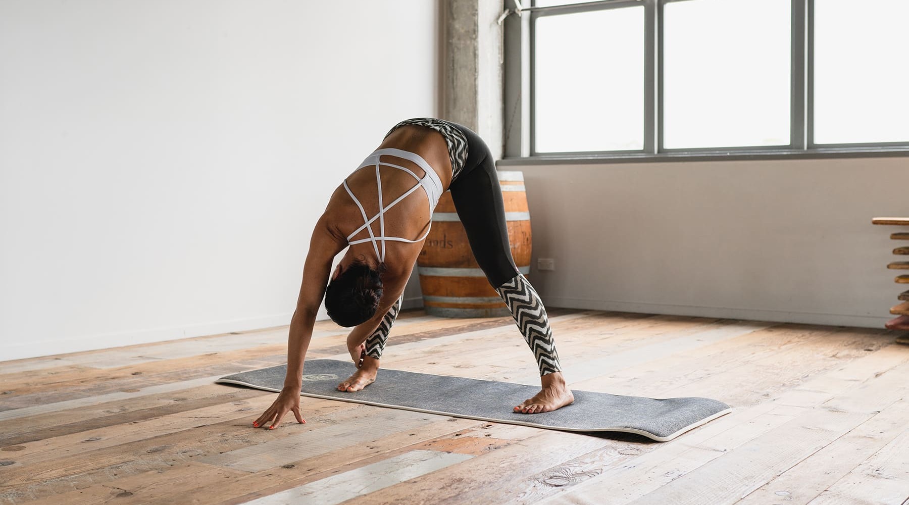 lifestyle image of a woman practicing yoga poses in a modern, wooden-floored room